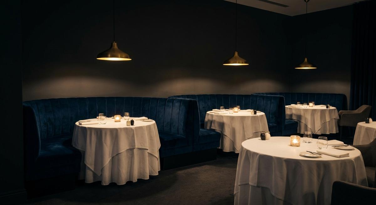 Candlelit dining room with velvet banquettes and brass pendants